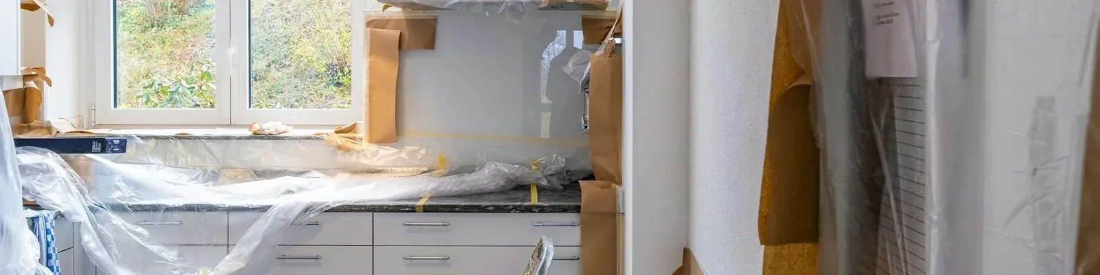A kitchen under renovation, cabinets covered in plastic